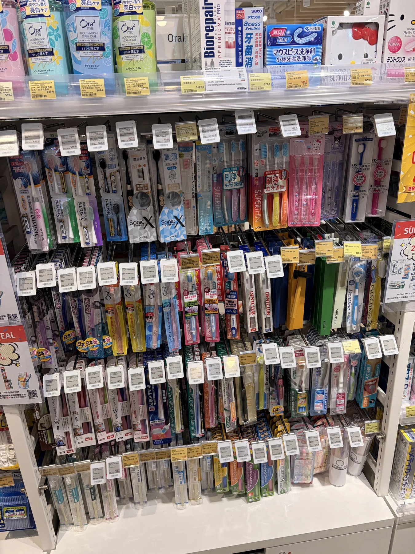 User-provided in-store PoC photograph of electronic labels installed among dense oral-care merchandise and existing paper labels.